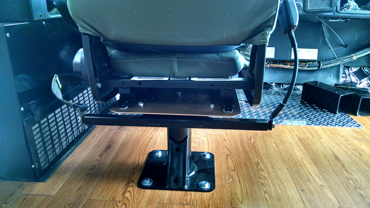 Custom made Skoolie driver's seat adapter plate in action.