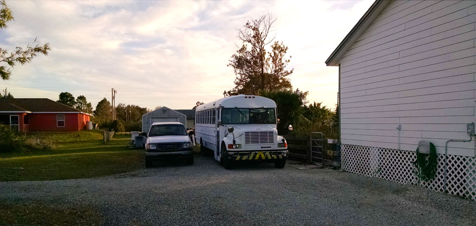 School bus parked in a driveway next to a pickup truck
